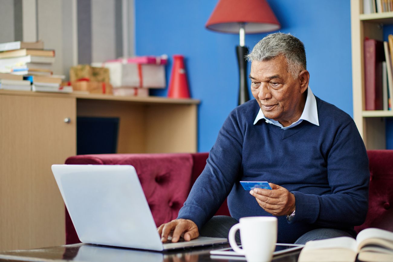 Man using online banking at computer holding credit card